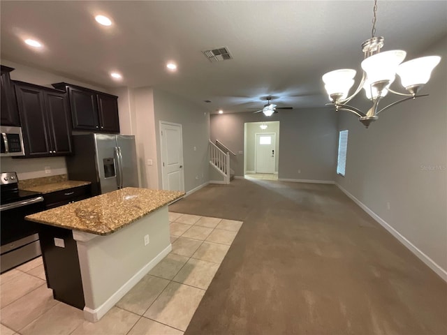 kitchen with pendant lighting, light tile patterned floors, stainless steel appliances, a center island, and light stone countertops