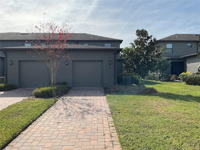 view of front of property featuring a garage, a front lawn, and central air condition unit