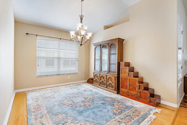 interior space featuring hardwood / wood-style flooring, vaulted ceiling, and an inviting chandelier