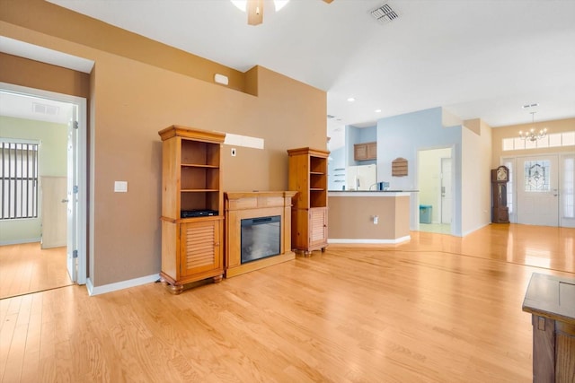 unfurnished living room with light hardwood / wood-style floors and ceiling fan with notable chandelier