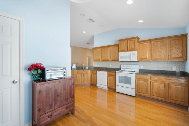 kitchen featuring white appliances, tasteful backsplash, sink, vaulted ceiling, and light hardwood / wood-style flooring