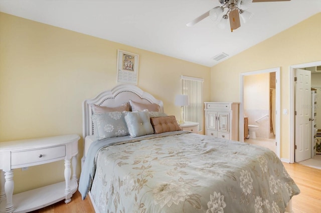 bedroom featuring light wood-type flooring, ceiling fan, lofted ceiling, and ensuite bath