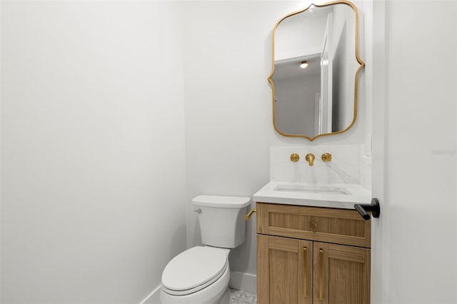 half bath with toilet, baseboards, and vanity