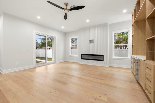 unfurnished living room with a large fireplace, light wood finished floors, a wealth of natural light, and recessed lighting