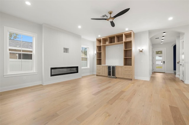 unfurnished living room with a large fireplace, wine cooler, light wood-style floors, and recessed lighting