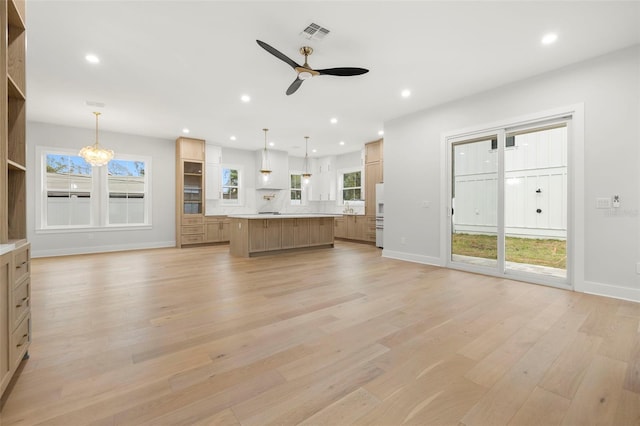 unfurnished living room with light wood-style floors, ceiling fan with notable chandelier, visible vents, and recessed lighting