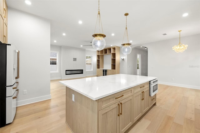 kitchen with arched walkways, recessed lighting, light wood-style flooring, freestanding refrigerator, and open floor plan