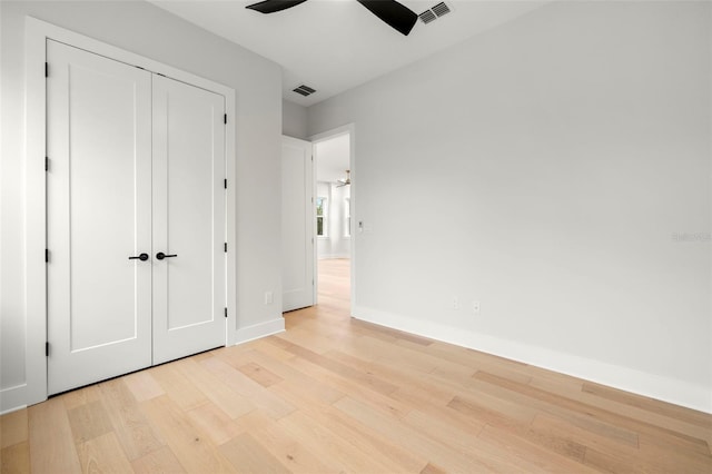 unfurnished bedroom featuring light wood finished floors, baseboards, visible vents, and a closet