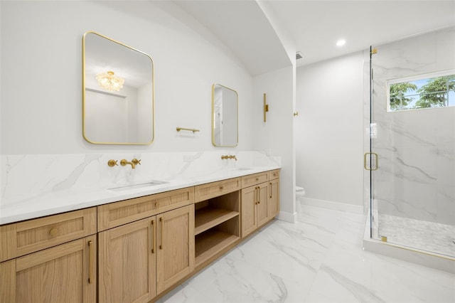 bathroom featuring toilet, a sink, marble finish floor, a marble finish shower, and double vanity