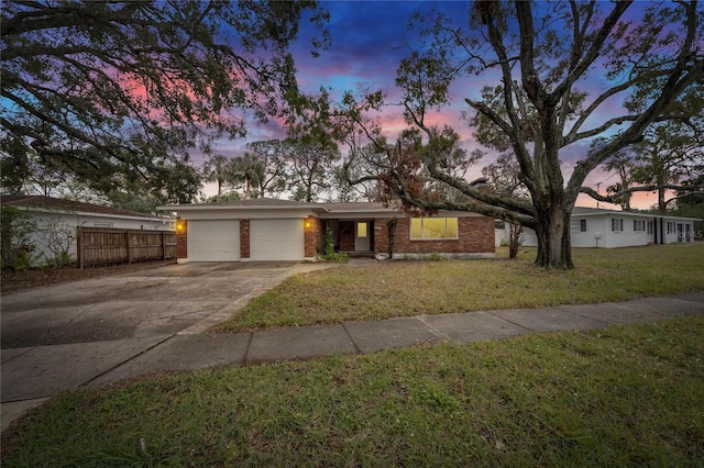 ranch-style house featuring a garage and a lawn