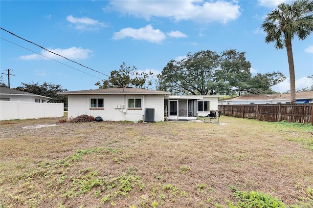 rear view of house with cooling unit, a patio, and a lawn