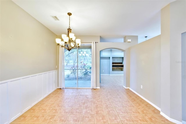 tiled spare room featuring a notable chandelier