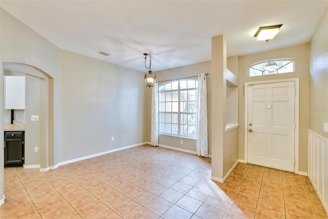 foyer entrance with light tile patterned floors and a notable chandelier