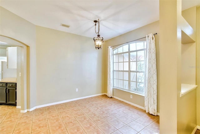 empty room with light tile patterned floors and an inviting chandelier