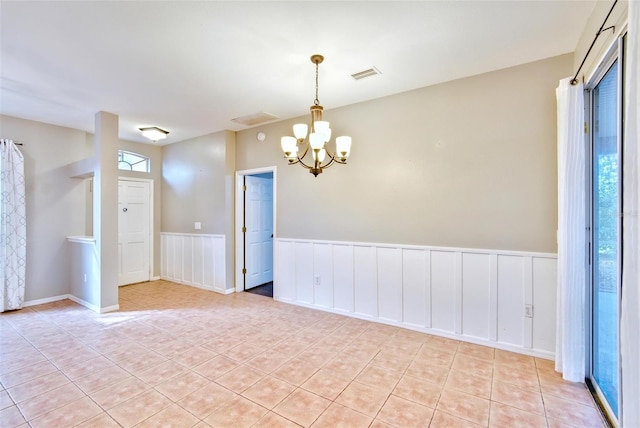 tiled spare room with a notable chandelier