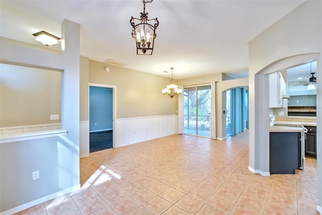 empty room with ceiling fan with notable chandelier and light tile patterned floors