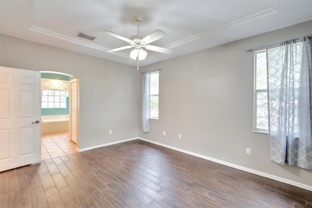 empty room featuring dark hardwood / wood-style floors, ceiling fan, and a raised ceiling