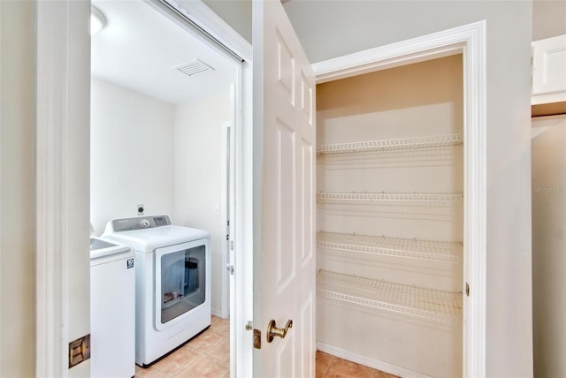 washroom with washer and clothes dryer and light tile patterned floors