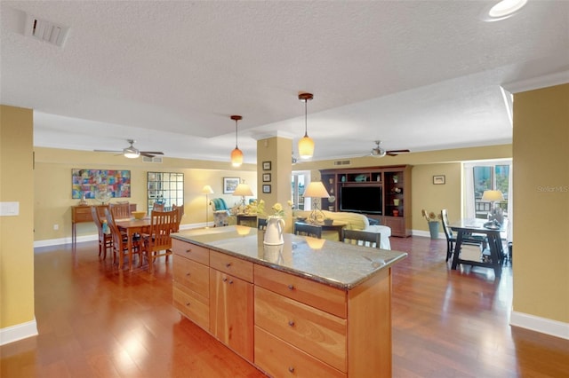 kitchen with hanging light fixtures, dark hardwood / wood-style flooring, a textured ceiling, and light brown cabinetry