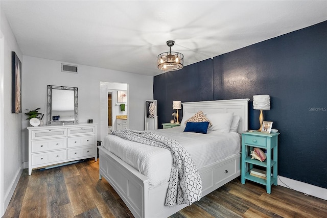 bedroom featuring dark wood-type flooring, connected bathroom, and a chandelier