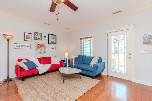 living room with ornamental molding, ceiling fan, and light wood-type flooring