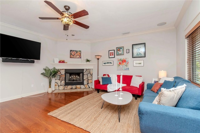 living room featuring crown molding, wood-type flooring, ceiling fan, and a fireplace