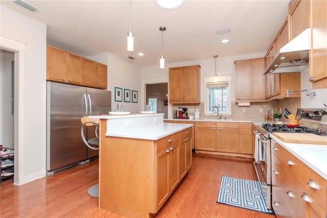 kitchen with light hardwood / wood-style flooring, decorative light fixtures, a kitchen island, and appliances with stainless steel finishes