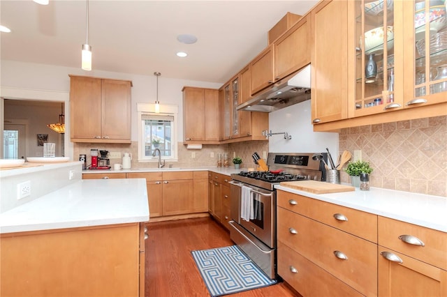 kitchen featuring dark hardwood / wood-style floors, sink, decorative backsplash, hanging light fixtures, and stainless steel gas range oven