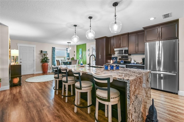 kitchen with sink, dark brown cabinets, a center island with sink, and stainless steel appliances