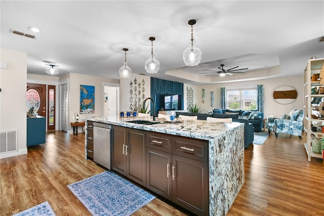 kitchen with dishwasher, decorative light fixtures, sink, a raised ceiling, and dark brown cabinets