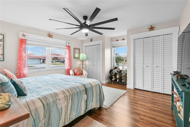 bedroom featuring dark wood-type flooring, two closets, and ceiling fan