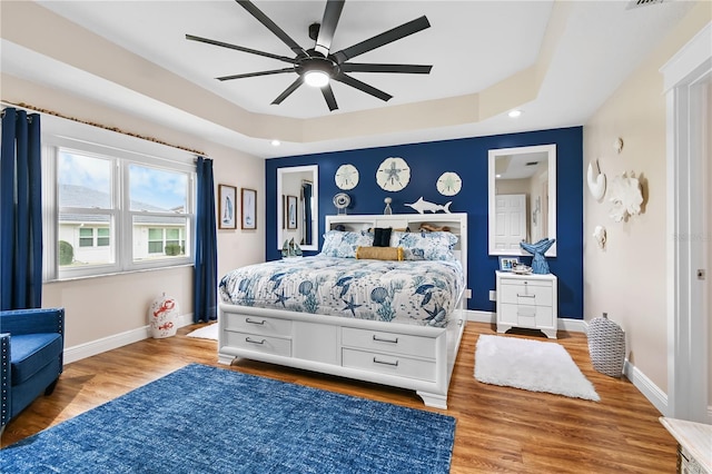 bedroom featuring ceiling fan, a raised ceiling, and hardwood / wood-style floors