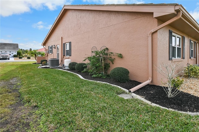 view of side of home featuring central AC unit and a yard