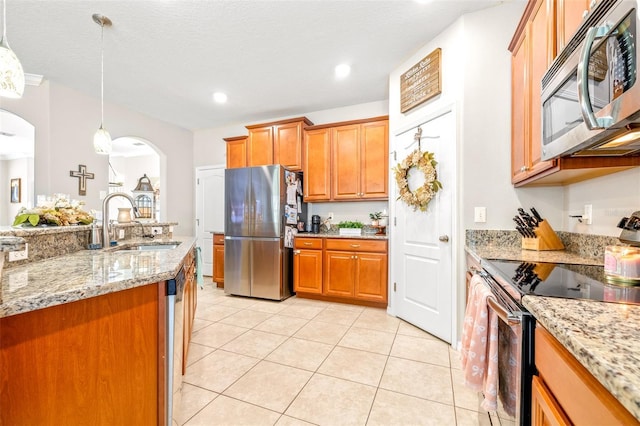 kitchen featuring light tile patterned flooring, pendant lighting, sink, stainless steel appliances, and light stone countertops