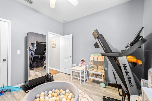 workout area with ceiling fan and light wood-type flooring