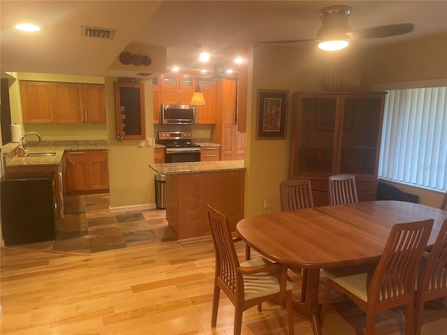 dining area featuring sink, ceiling fan, and light wood-type flooring