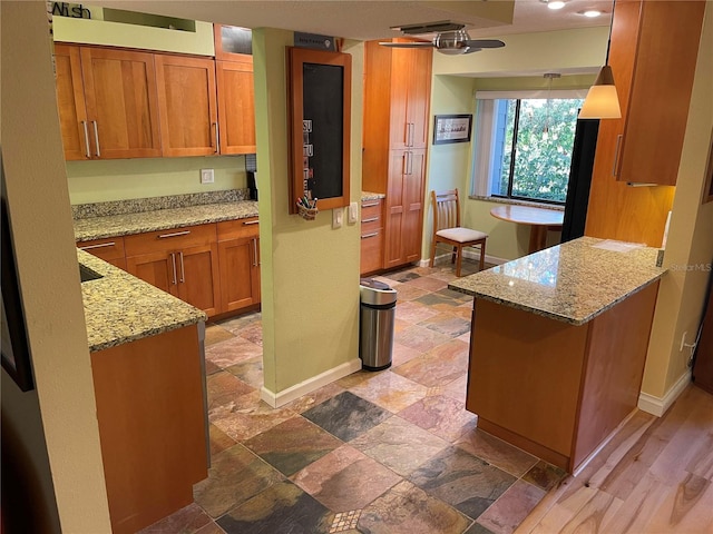 kitchen featuring ceiling fan, light stone counters, and kitchen peninsula