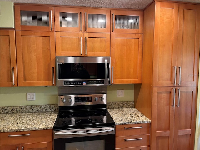 kitchen featuring light stone countertops, a textured ceiling, and appliances with stainless steel finishes