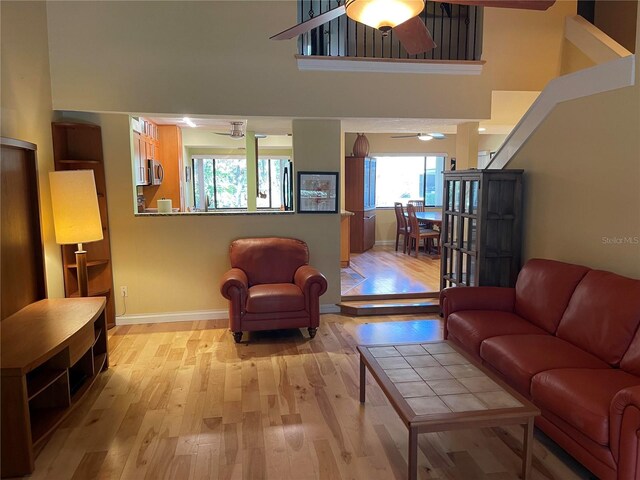 living room featuring ceiling fan, light hardwood / wood-style flooring, and a high ceiling