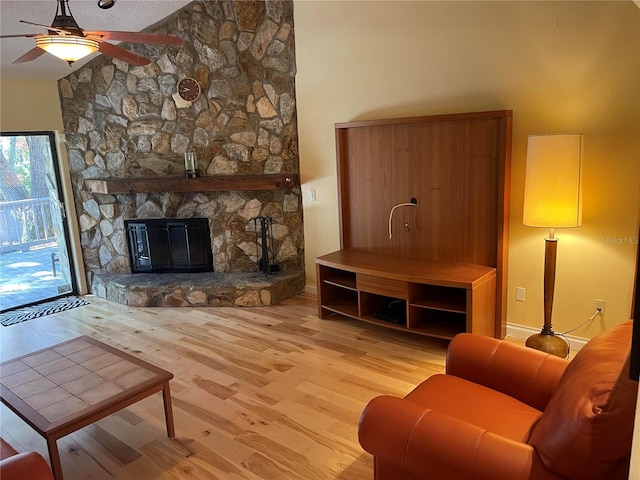 living room with a stone fireplace, vaulted ceiling, ceiling fan, and hardwood / wood-style flooring