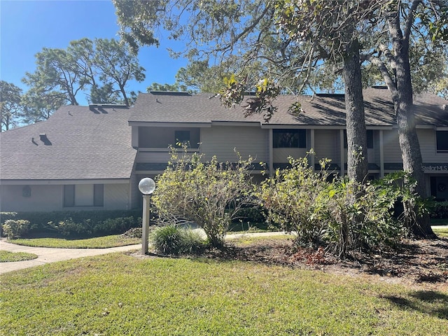 view of front of home with a shingled roof and a front lawn