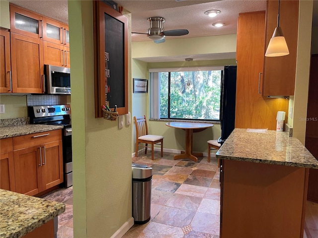 kitchen with brown cabinetry, glass insert cabinets, appliances with stainless steel finishes, a center island, and decorative light fixtures