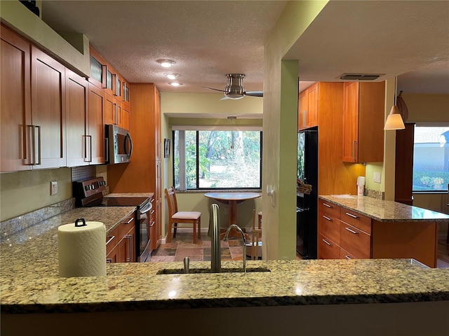 kitchen featuring light stone counters, brown cabinets, visible vents, appliances with stainless steel finishes, and glass insert cabinets