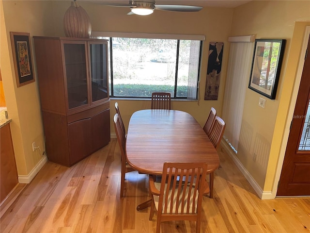 dining space featuring light wood-type flooring, baseboards, and a ceiling fan