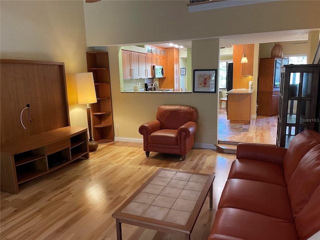 living area with a towering ceiling, light wood-style flooring, and baseboards