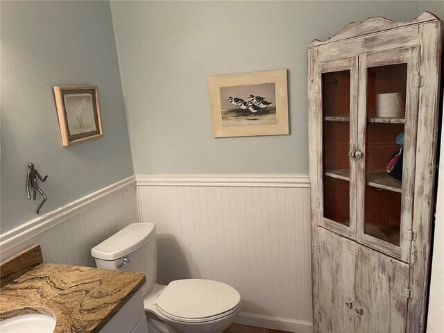 bathroom with toilet, vanity, and wainscoting