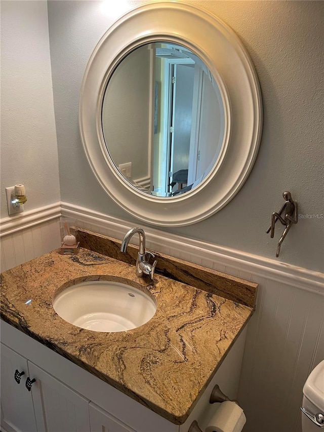 details with a wainscoted wall and vanity