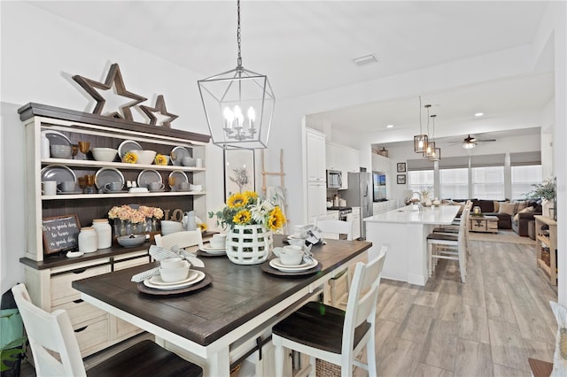 dining area featuring light hardwood / wood-style floors, sink, and ceiling fan with notable chandelier