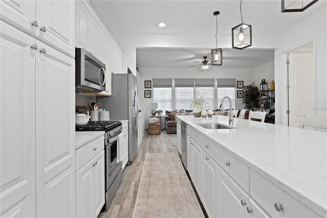 kitchen featuring decorative light fixtures, sink, white cabinets, and stainless steel appliances