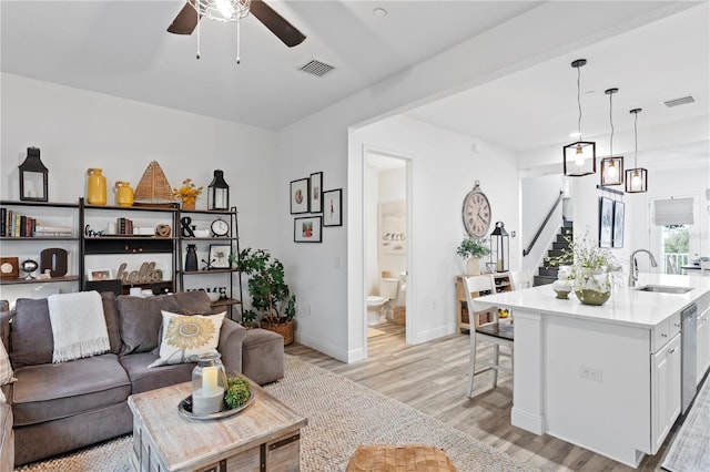 living room featuring sink, light wood-type flooring, and ceiling fan